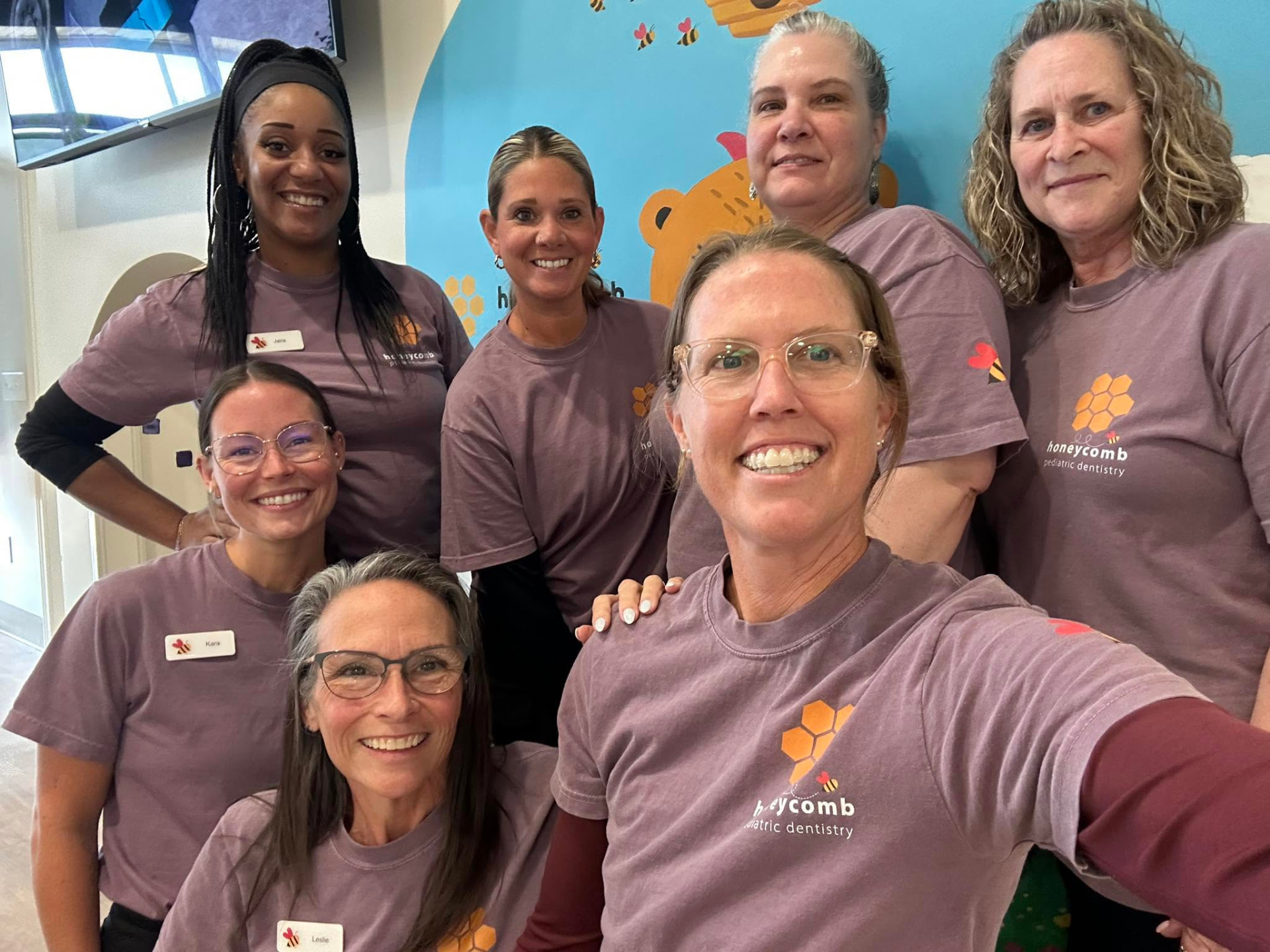 The Honeycomb Pediatric Dentistry team of six smiling women in matching honeycomb logo shirts inside the Ozark, MO office